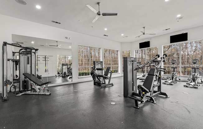A spacious gym with various exercise equipment and a mirrored wall.
