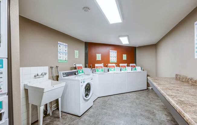 A laundry room with a washer and dryer, a sink, and a counter.