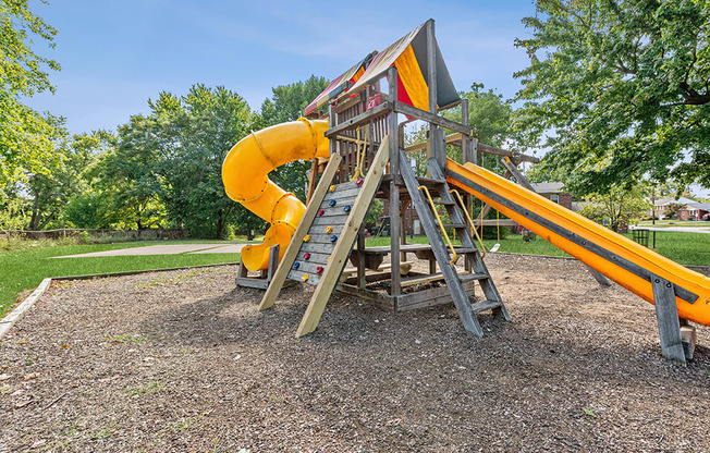 a swing set with a yellow slide in a park