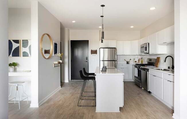 A modern kitchen with white cabinets and a black door.