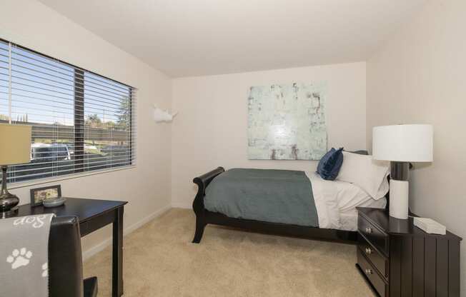a bedroom with a bed and a desk and a window at Rocklin Manor Apartments, California, 95677