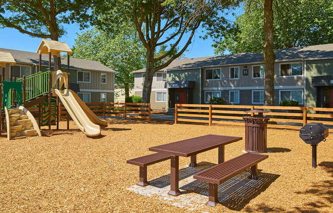 a playground with a slide and a picnic table in front of apartments  at Woodhaven, Everett, Washington