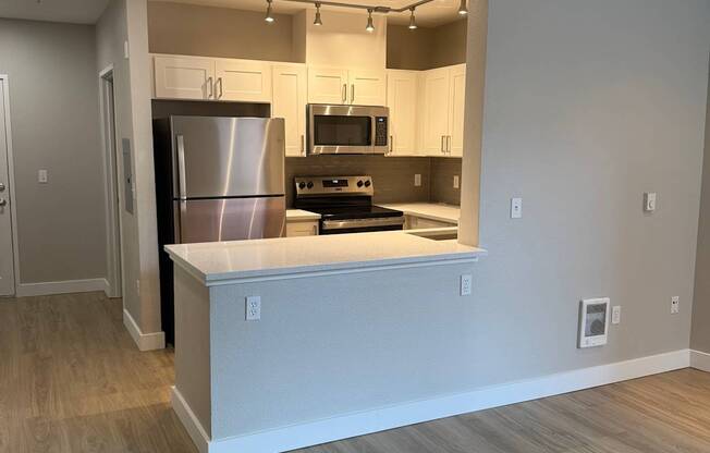 A modern kitchen with a stainless steel refrigerator and wooden accents on the walls.
