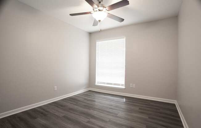 an empty living room with a ceiling fan and a window