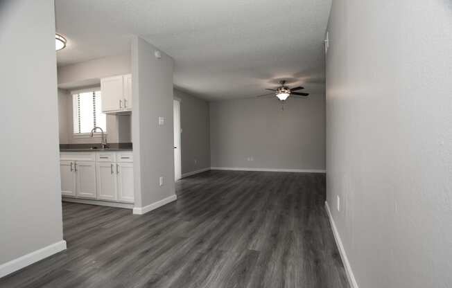 an empty living room and kitchen with a ceiling fan