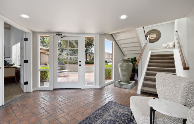 a living room with two chairs and a staircase with glass doors