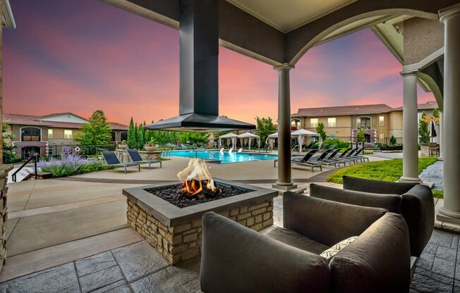 a patio with a fire pit and chairs and a pool