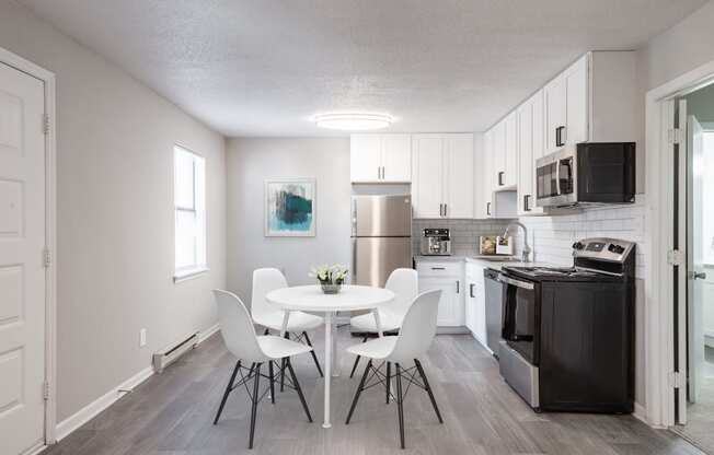 a dining area with a table and chairs and a kitchen in the background