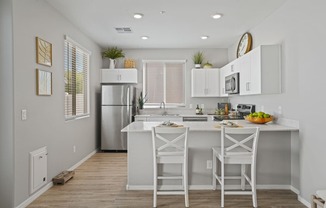 a kitchen with white cabinets and a white island with stools