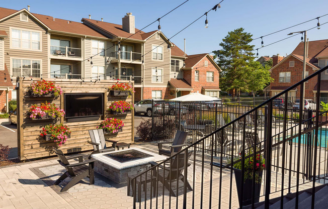 a patio with a fire pit and chairs in front of an apartment building