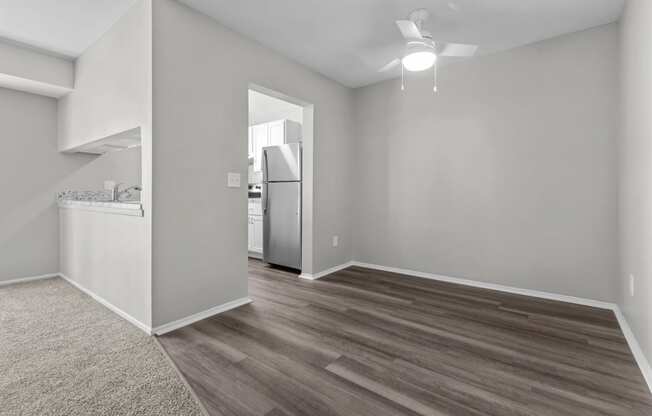 the living room and kitchen of an apartment with grey walls and wood flooring