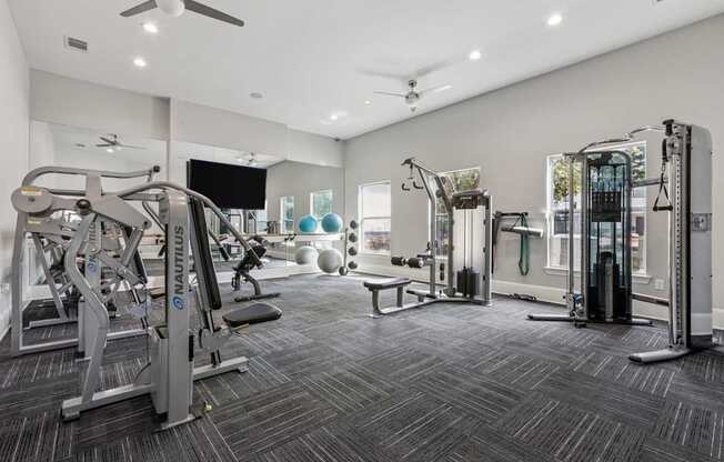 A spacious gym with a variety of equipment including treadmills, weight machines, and a bench.