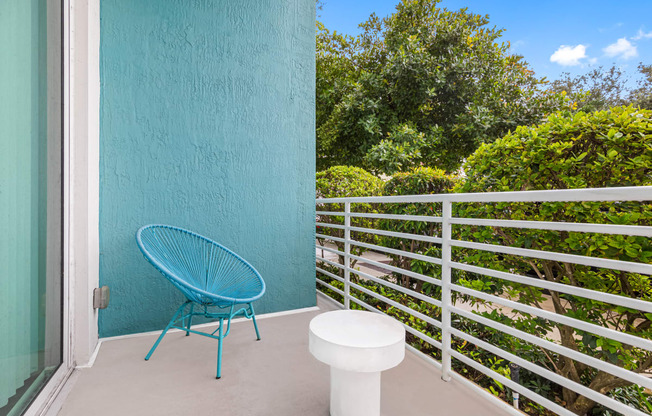 a patio with a blue chair and a stool on a balcony
