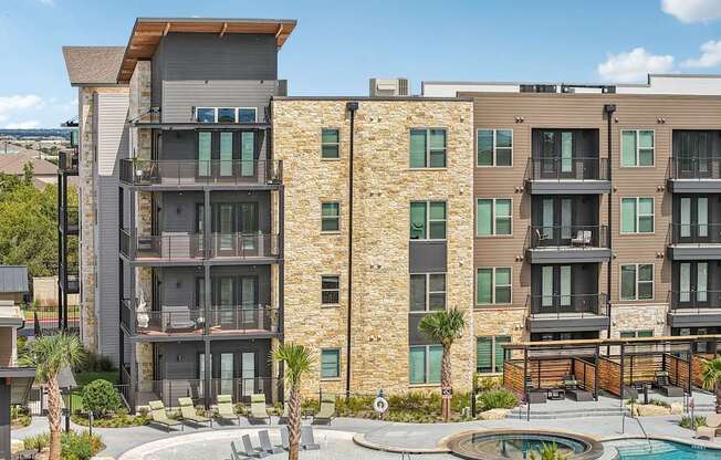 A modern apartment complex with a pool in the courtyard.