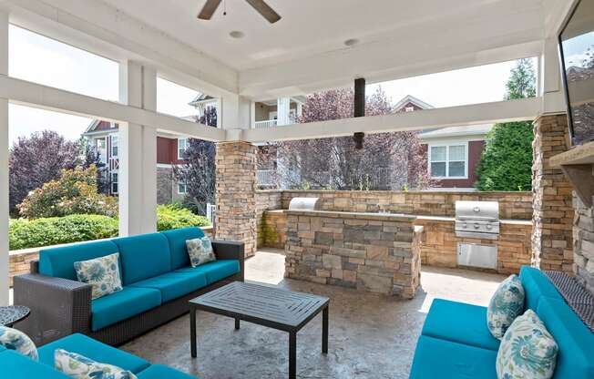 a covered patio with blue couches and a stone wall