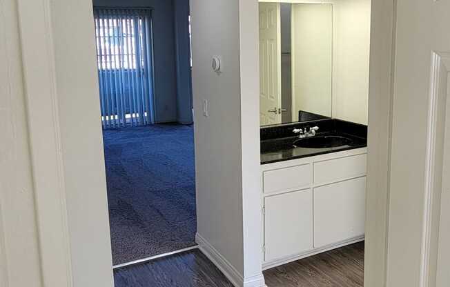 Hallway view of bathroom vanity and door to toilet and bathtub at Northwood Apartments in Upland, California.