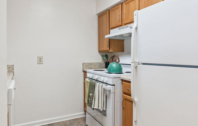 A kitchen with white appliances and wooden cabinets.