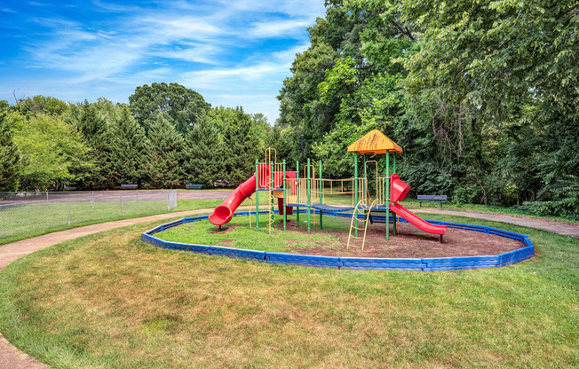 a playground with a blue trampoline and red slides