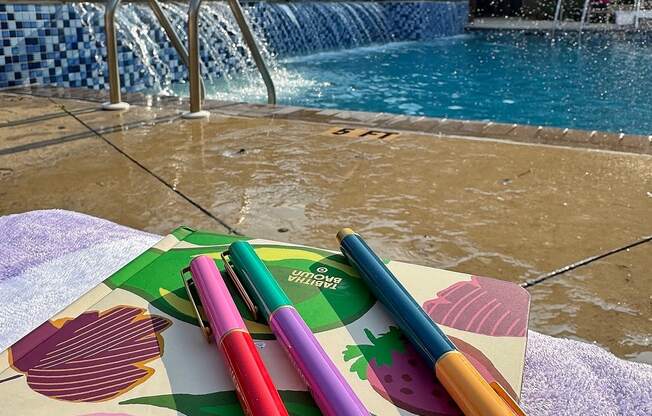 A pool with a waterfall and a table with four pens on it.