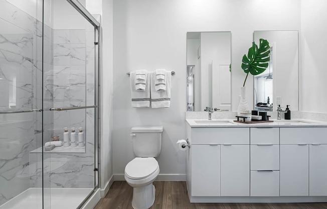 A white toilet sits in a bathroom with a marble floor and a glass shower.