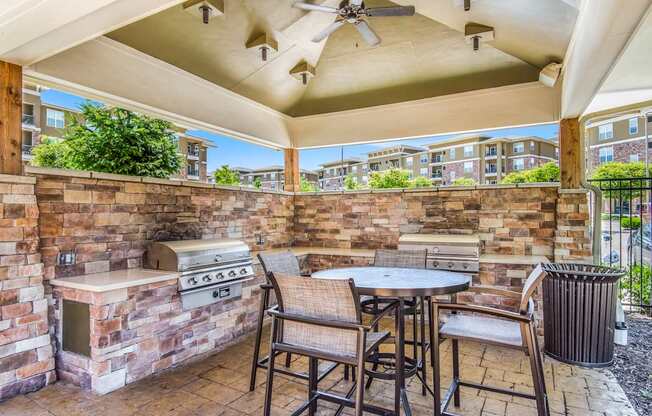 A patio with a table, chairs, and a grill.