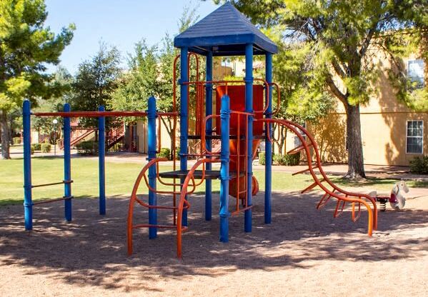 Multi Colored Playground in Shaded Courtyard with Tall Trees