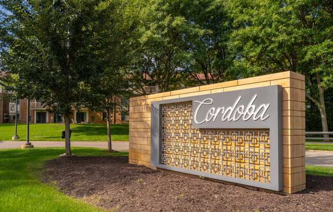 a sign that says corolla in front of a brick wall with trees in the background