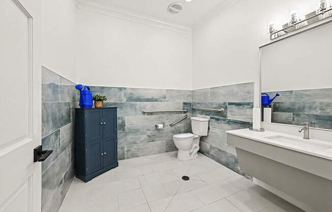 A bathroom with a toilet, sink, and a blue cabinet.