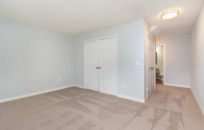 an empty living room with a white door and a closet
