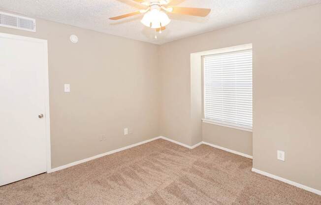 A room with a ceiling fan and carpeted floor.