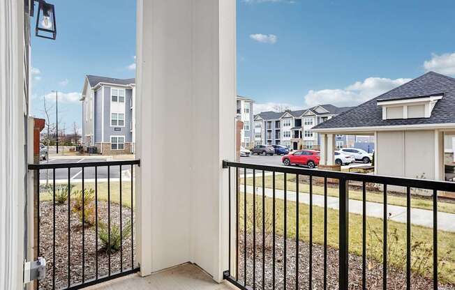A view from a balcony looking out at a row of houses and cars.
