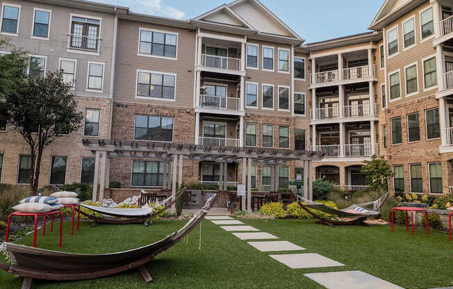 A large grassy area in front of apartment buildings with a boat-shaped seating area.
