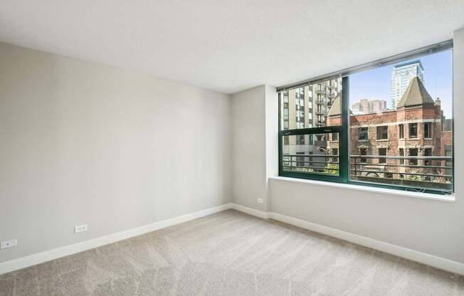 Empty room with a large window overlooking a cityscape.