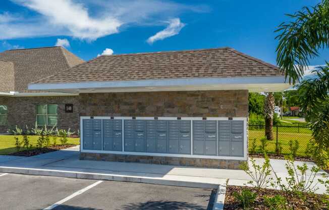 A building with a grey roof and a stone wall with a row of mailboxes in front at Mode at Melbourne, LLC Apartments, Melbourne