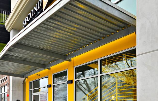 The entrance to a building with a yellow awning and glass doors.