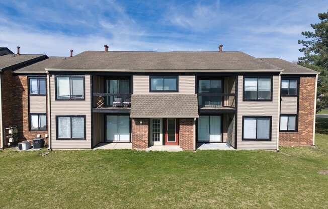 a large apartment building with a lawn and a blue sky