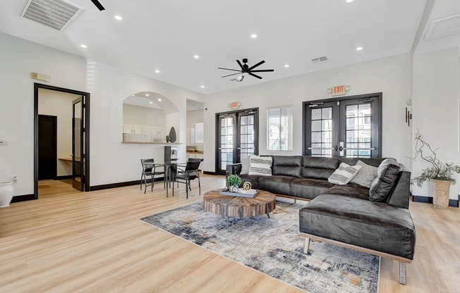 A living room with a black couch and a wooden floor.