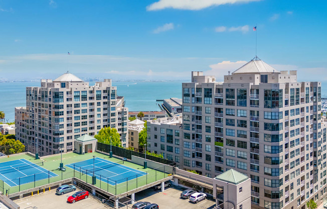 A tennis court is located between two buildings.