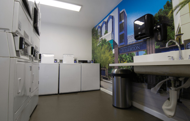 A wall mural of a street scene is displayed in a laundromat.
