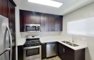 a kitchen with dark wood cabinets and stainless steel appliances