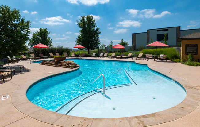 a resort style pool with lounge chairs and umbrellas
