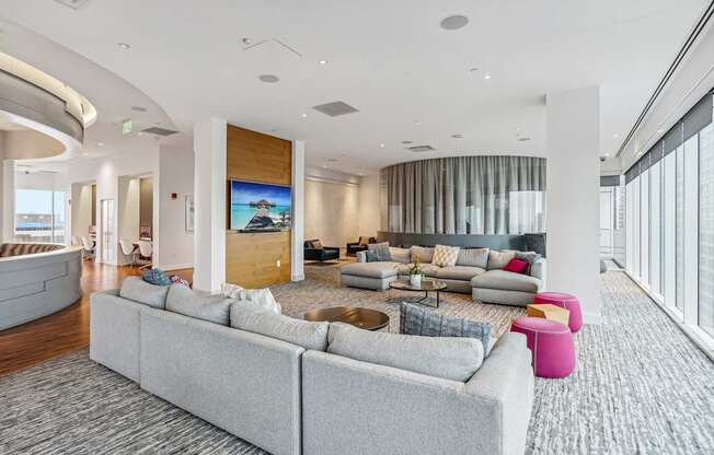 A modern living room with a grey sofa and a large screen on the wall.