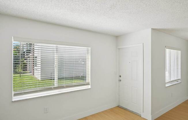 A room with a white door and a window with blinds.