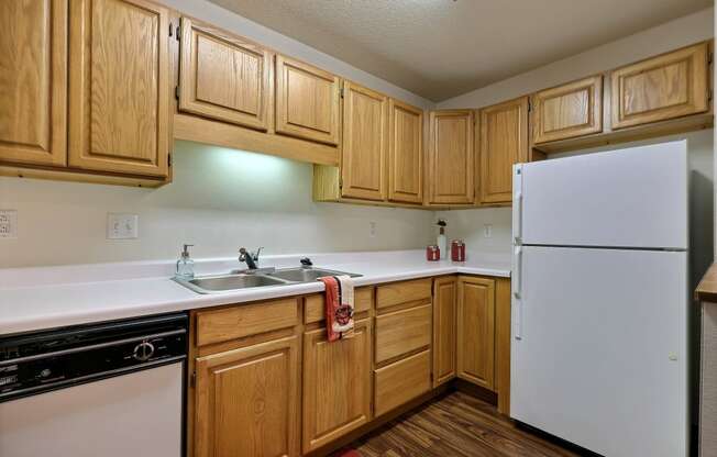 A kitchen with white appliances and wooden cabinets. Fargo, ND Flagstone Apartments.