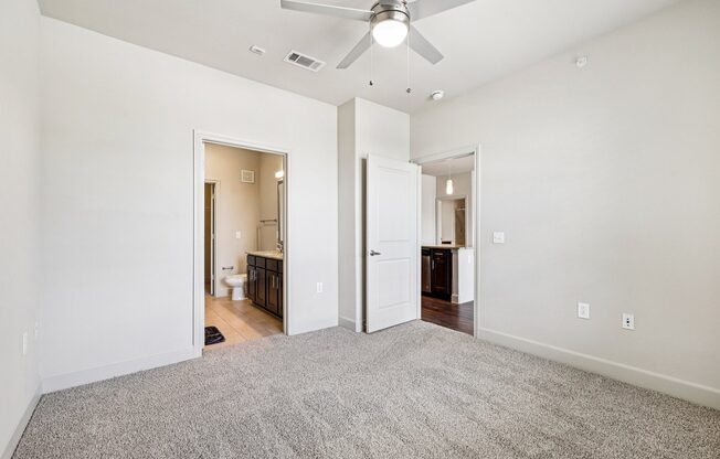 A room with a ceiling fan and carpeted floor.