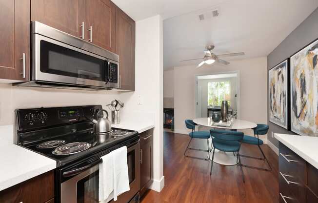 Kitchen with a stove and microwave and a dining table with chairs at Folsom Ranch Apartments in California