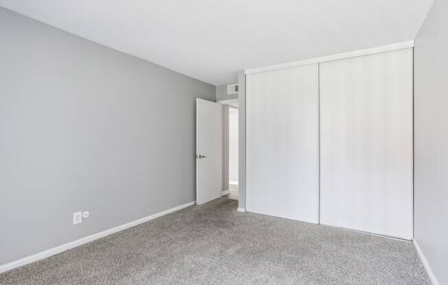 an empty room with white closet doors and a carpeted floor