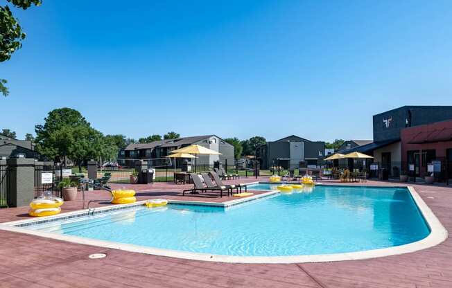 Community swimming pool at Fusion Fort Worth apartments in Haltom City, TX with yellow inflatables and lounge chairs with umbrellas