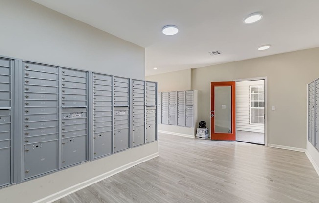 A room with grey lockers and a red door.
