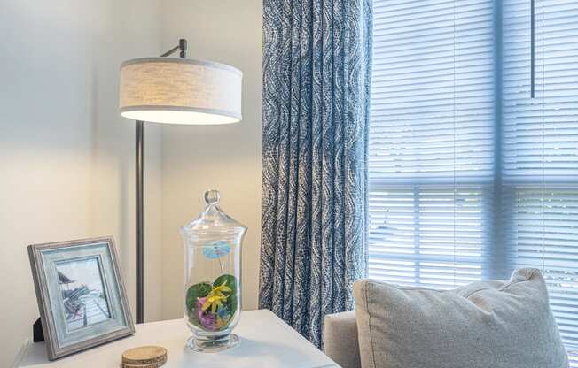 a corner of a room with a window and a table with a vase with